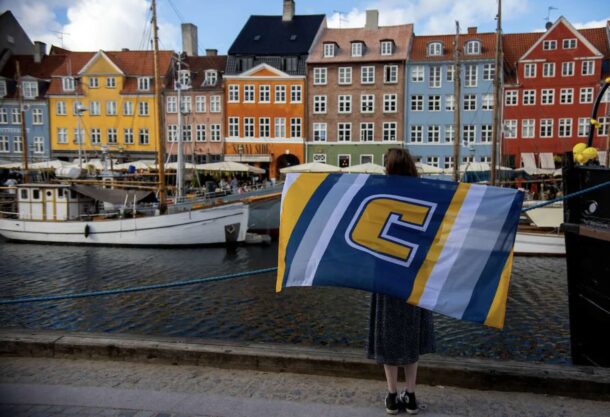 Sydney Banks holds the UTC flag in front of the Nyhavn Canal in Copenhagen. Photo by Clara Paulson.